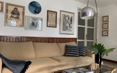 Nel living di questa casa degli anni 60’ domina alle pareti una bella boiserie in legno. Tra i molti quadri della padrona di casa è stata individuata una selezione declinata sugli azzurri suggerita dal tappeto a righe in lana. L’effetto voluto rinnova lo spazio dedicato al relax davanti al lago, mixando mobili anni 80’, vintage e piccoli tavoli etnici.